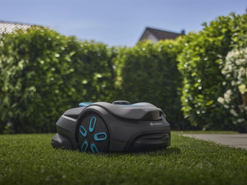 GARDENA smart SILENO sense 400 fährt auf dem Rasen, Hecke im Hintergrund