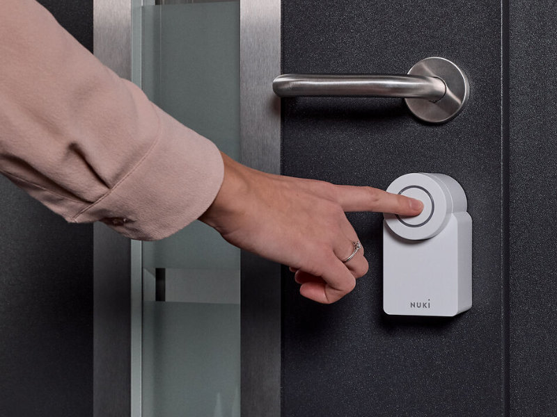 Nuki Smart Lock Go an der Tür - Knopf wird von Frau gedrückt
