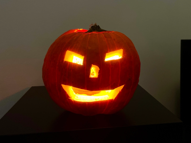 Kürbis mit geschnitzter Grimasse und Smart Home Lampe im Inneren