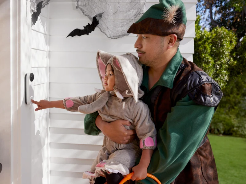 Vater und Tochter in Halloween-Kostümen klingeln an Videotürklingel