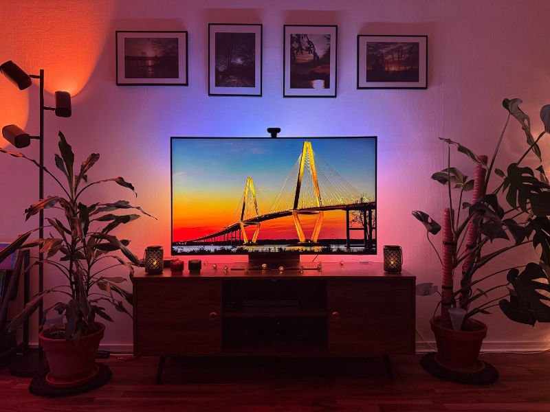 Fernseher zeigt Bild von imposanter Brücke bei Sonnenuntergang mit dunkelblauem Himmel darüber; Govee TV-Backlight leuchtet den Hintergrund akkurat aus.