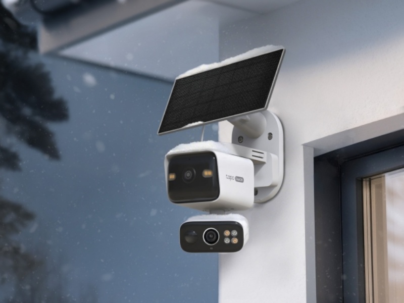 Weiße TP-Link Tapo AI-Überwachungskamera mit schwarzem Solarpanel, leicht mit Schnee bedeckt, an einer Außenwand montiert. Das wasser- und staubgeschützte System der Schutzklasse IP65 funktioniert auch bei starken winterlichen Niederschlägen.