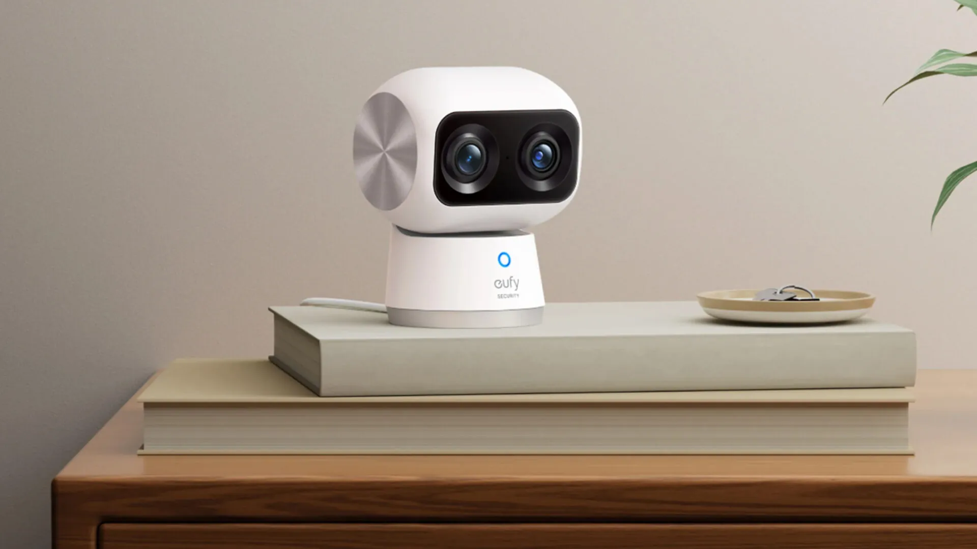 eufy Indoor Cam S350 und Schale mit Schlüsseln auf zwei Büchern auf einer Holzfarbenen Kommode