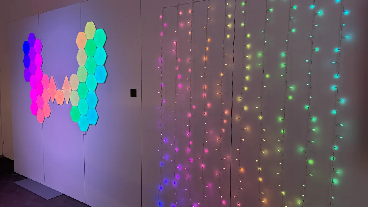 Sechseckige LED-Wandpaneele und Lichterketten, die einen lebendigen Farbverlauf in Regenbogenfarben zeigen.