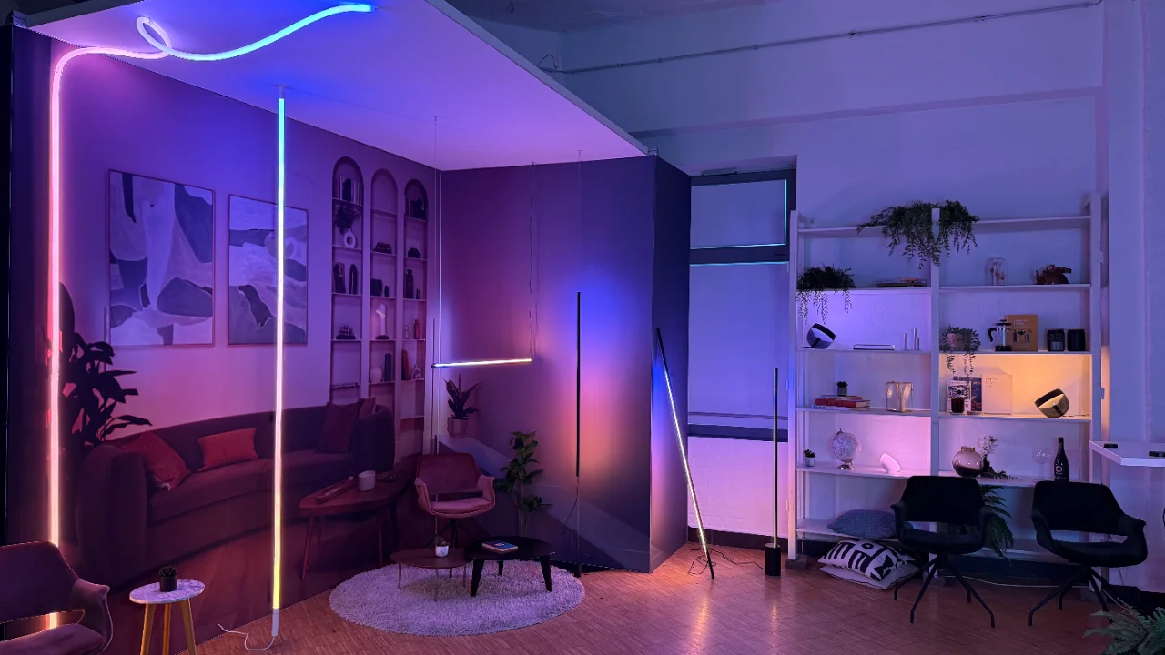 Eine intelligente Beleuchtung in leuchtenden Farben erhellt ein modernes Wohnzimmer mit farbenfrohen Neonstreifen und stimmungsvollen Stehlampen.
