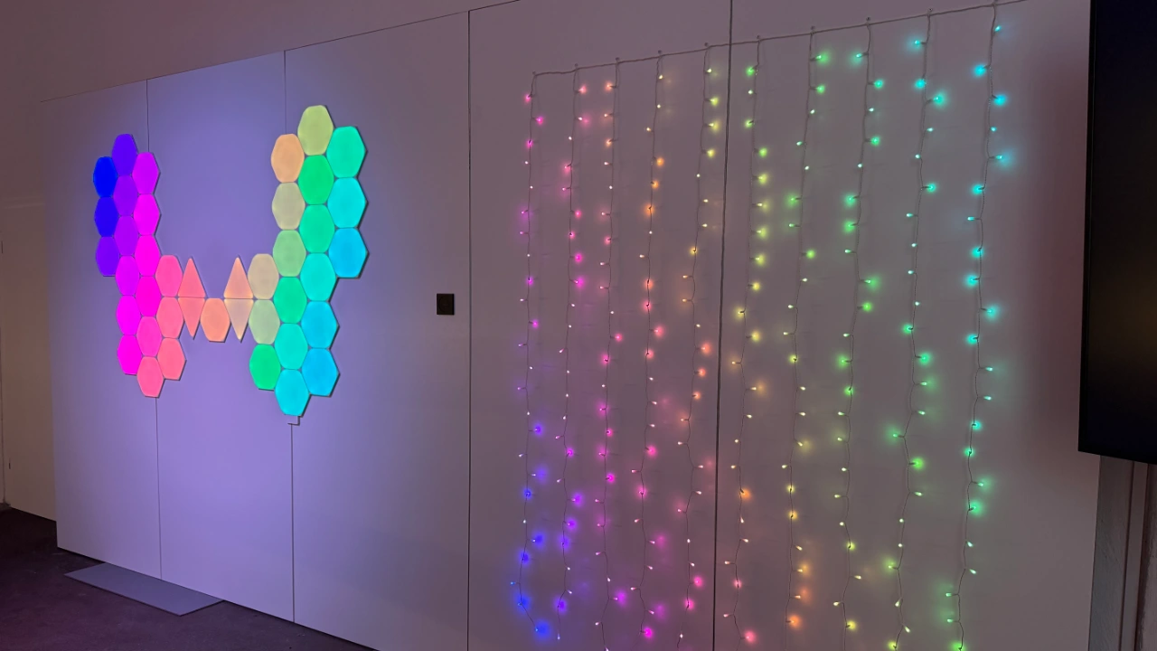 Nanoleaf Shapes und Curtain leuchten an weißer Wand in bunten Farben über das Philips Hue System