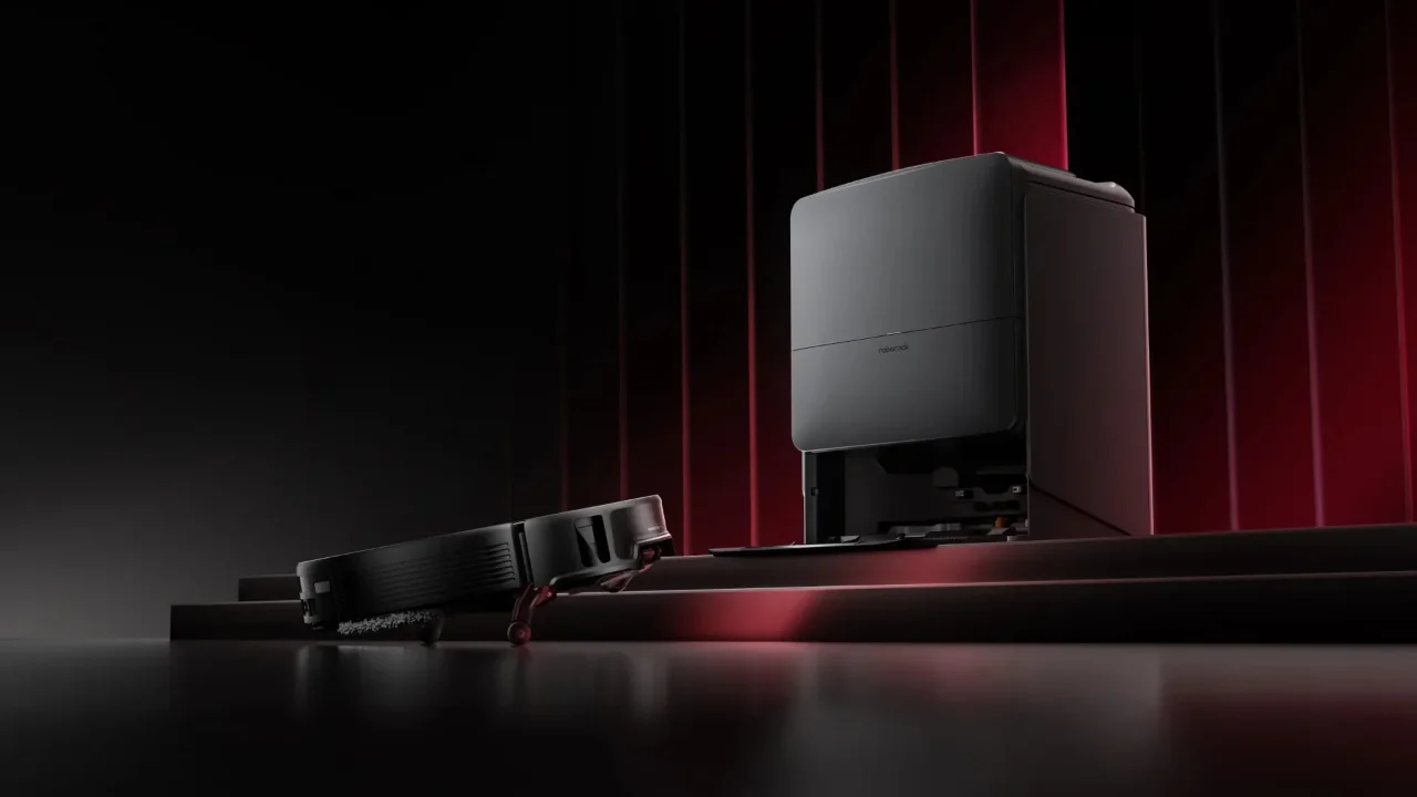 Ein eleganter schwarzer Roborock-Staubsaugerroboter und eine Ladestation auf einer dunklen Bühne mit dramatischer roter Beleuchtung.