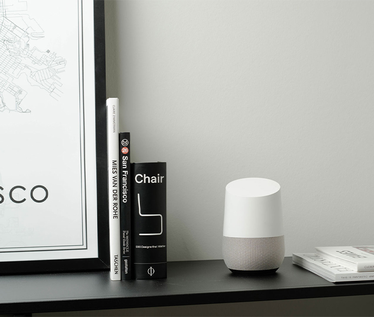 Google Home smarter Sprachassistent auf regal neben Büchern