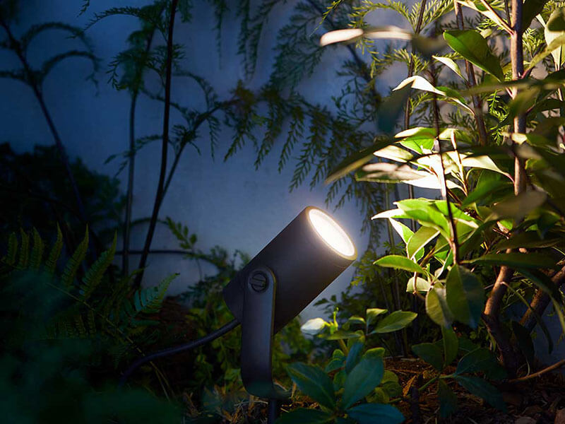 Philips Hue LED Spot Lily neben Hauswand und Pflanze