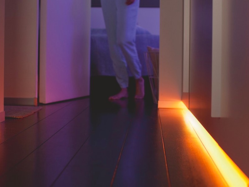 Person geht neben einem Lightstrip in ihr Zimmer.