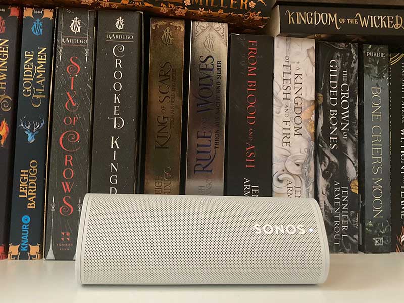 Sonos Roam liegend in Buecherregal mit Buechern