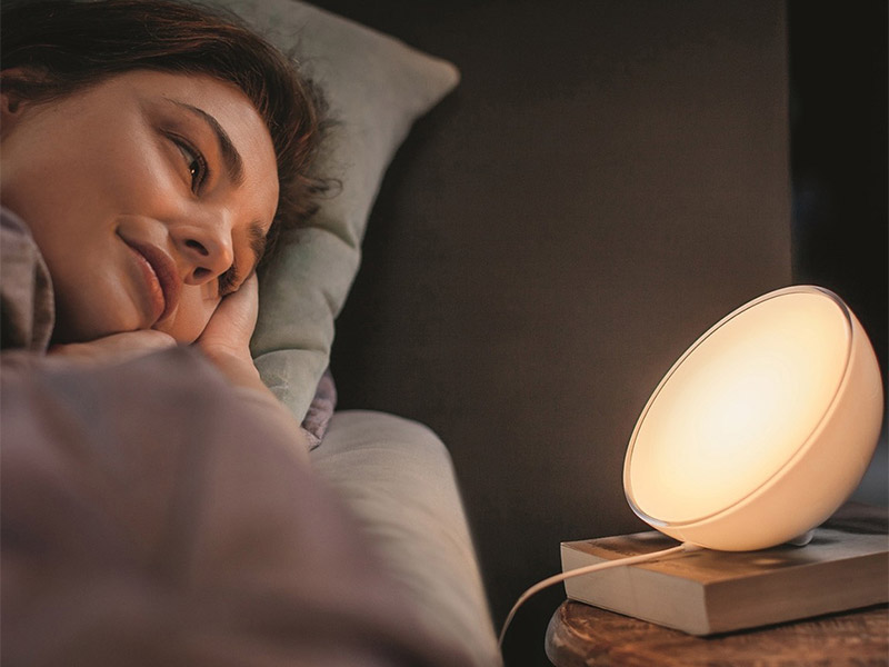 Frau liegt neben einer Philips hue go lampe im bett am valentinstag