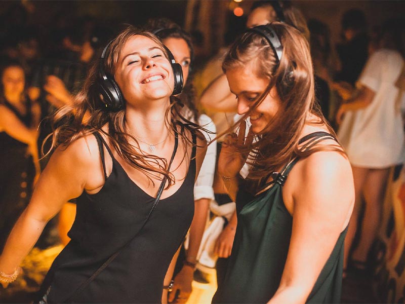 Frauen tanzen mit Kopfhörern auf einer silent Disco.