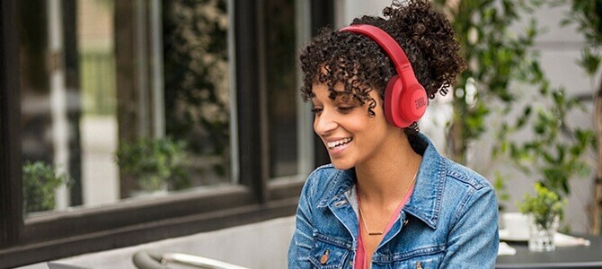 Frau mit roten JBL-Over-Ear-Kopfhörern